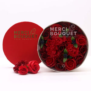 Red flowers in a 'Merci Bouquet' container on a white background